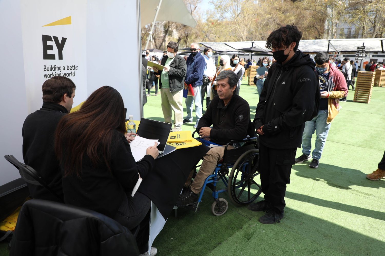 Persona en silla de ruedas inscribiéndose en una feria laboral.